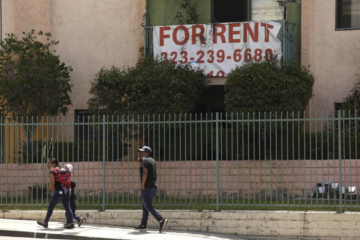 Pedestrians walk past an apartment complex in the Westlake neighborhood of Los Angeles in June