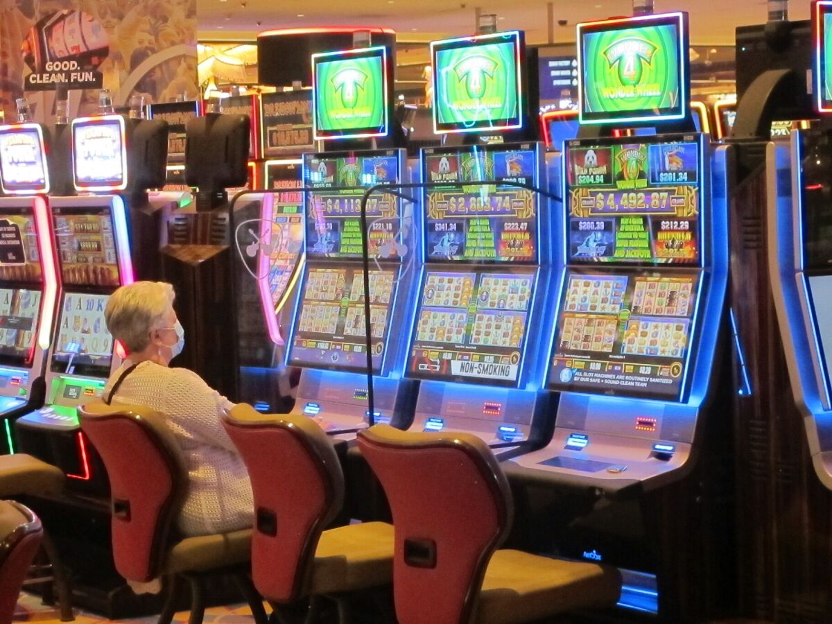In this May 3, 2021 photo a woman plays a slot machine while wearing a mask in the Hard Rock casino in Atlantic City, N.J. On May 11 the American Gaming Association released statistics showing that the U.S. commercial casino industry matched its best quarter ever in terms of revenue in the first three months of 2021, taking in more than $11.1 billion as customers continued returning amid the COVID-19 pandemic. (AP Photo/Wayne Parry)