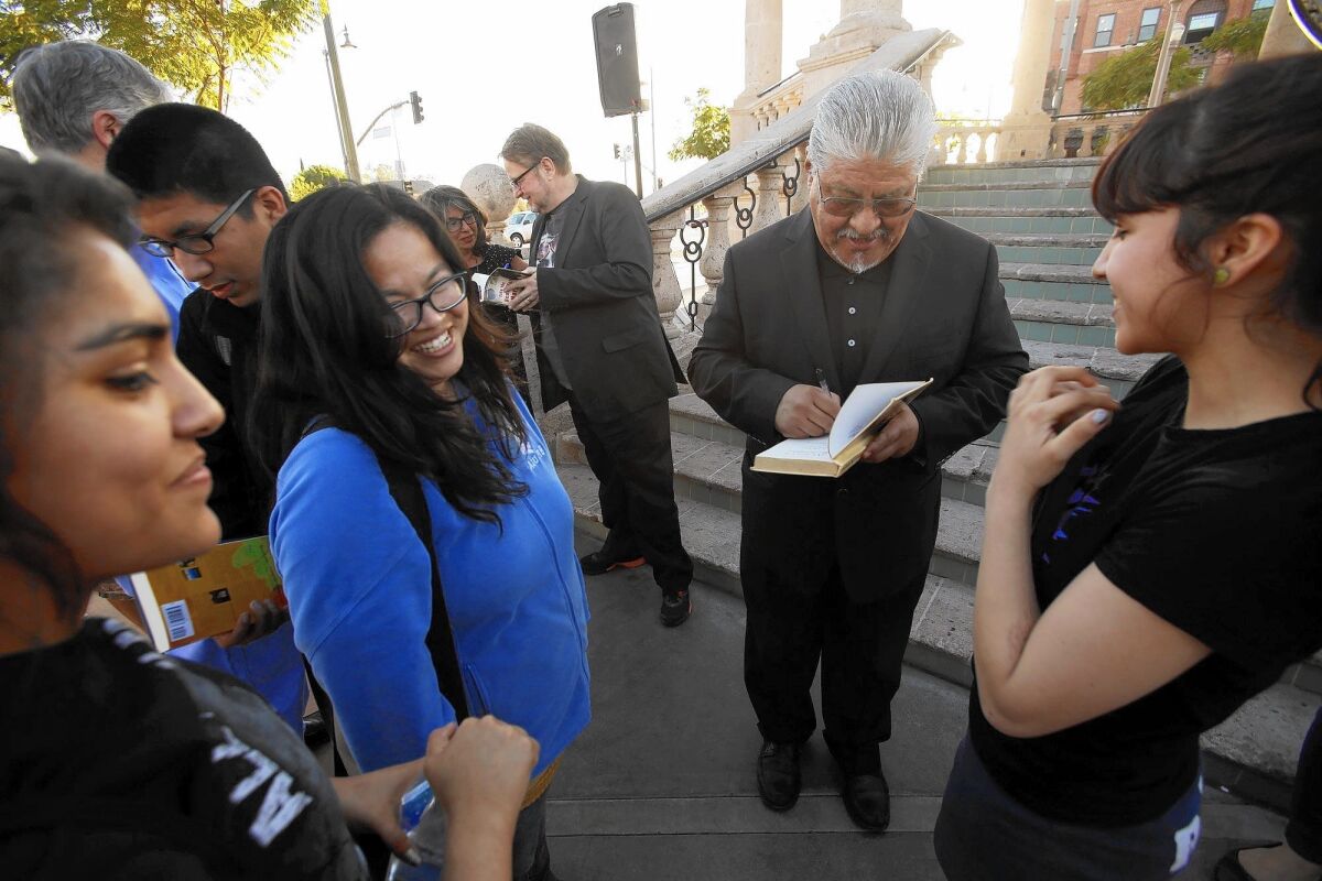 Author Luis Rodriguez, second from right, signs a copy of one of his books for a member of the Mendez High School Reading Club at Mariachi Plaza in Boyle Heights.