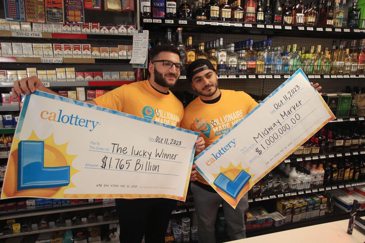 Two men pose with oversize lottery checks behind the counter at a liquor store