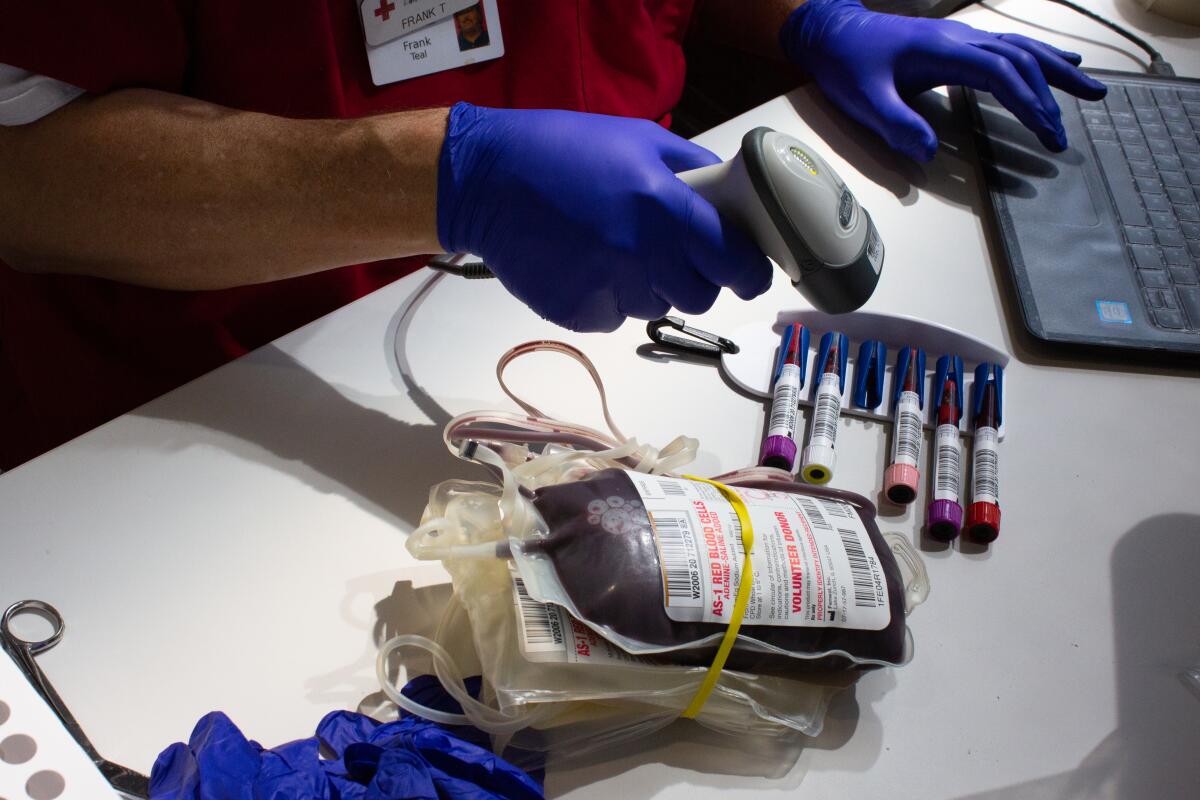 A technician scans vials and bags of donated blood.