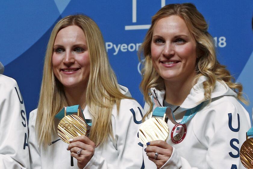 Monique Lamoureux-Morando (far left) and her twin Jocelyne Lamoureux-Davidson pose with teammates and their gold medals from the 2018 Winter Olympics.