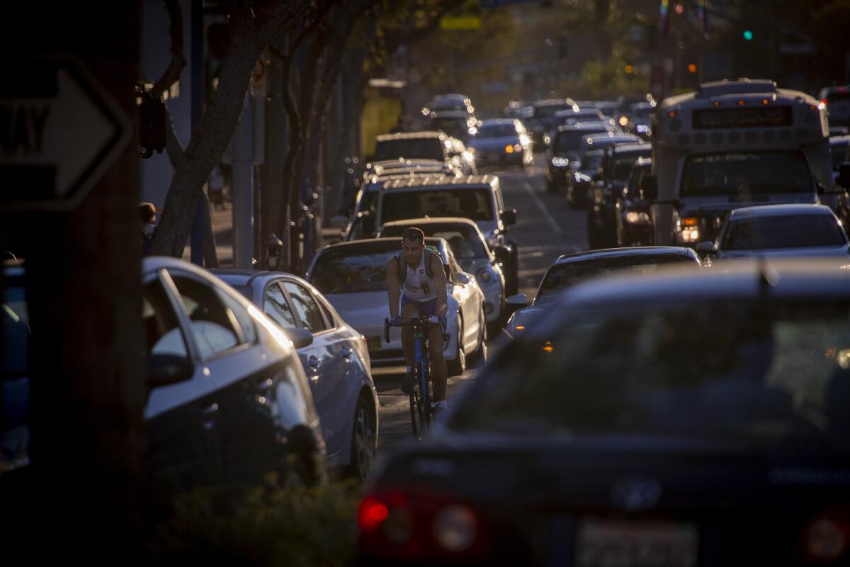 A cyclist rides in the bike lane as traffic backs up along Santa Monica Boulevard in West Hollywood on Oct. 28, 2021.