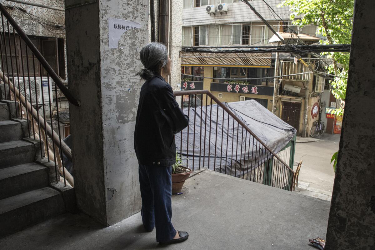 A woman in Wuhan stands just outside her apartment. Residents feared new limits on movement.