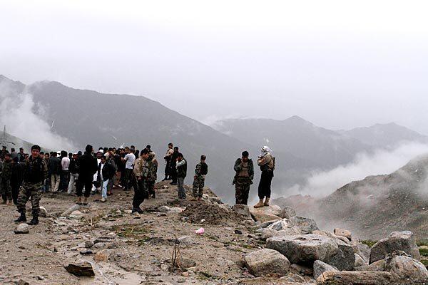 Afghans stand near where a passenger plane is believed to have gone down amid the jagged peaks of the nearly 13,000-foot-high Salang Pass.