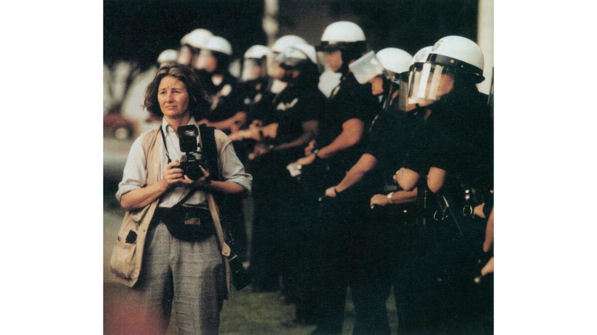 Los Angeles Times staff photographer Rosemary Kaul walks in front of police officers guarding Parker Center.