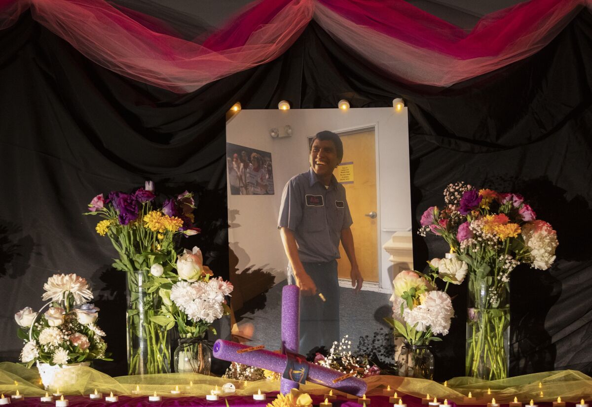 A photo of a man in a work uniform is surrounded by vases with flowers and votive candles.