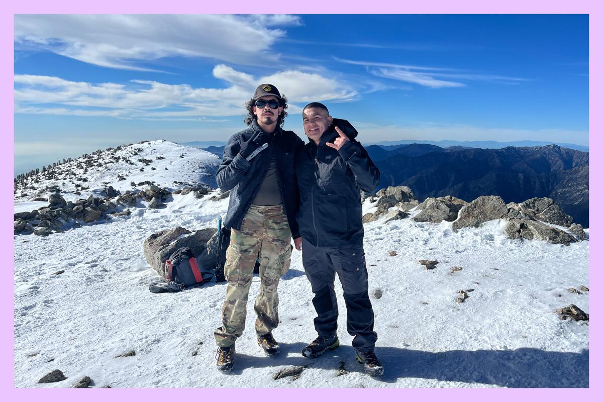 Two men make triumphant hand gestures at the summit of Mt. Baldy.