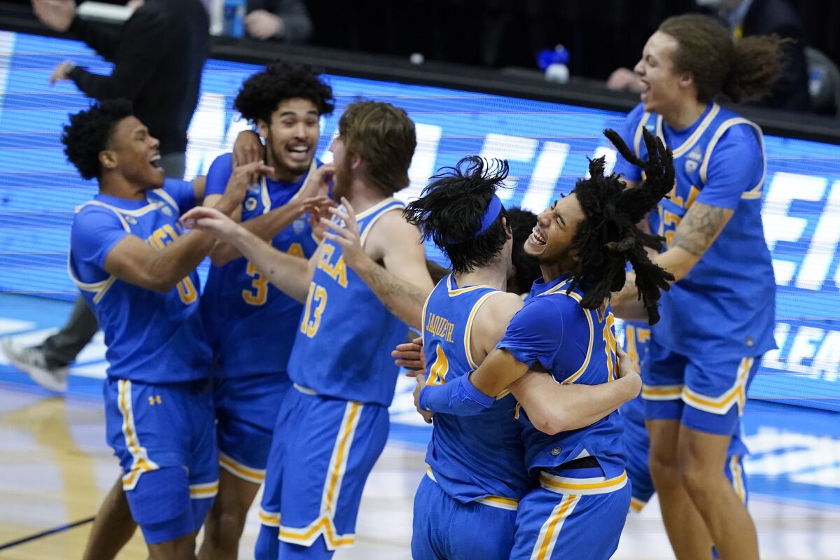 FILE - UCLA guard Tyger Campbell, right, celebrates with teammate guard Jaime Jaquez Jr. (4) after an Elite 8 game against Michigan in the NCAA men's college basketball tournament at Lucas Oil Stadium, in Indianapolis, in this Wednesday, March 31, 2021, file photo. UCLA won 51-49. UCLA is an overwhelming favorite to win the Pac-12 after reaching the Final Four last season. The Bruins' men's basketball team received 32 votes from 34 media members who cover the league in the preseason poll. (AP Photo/Darron Cummings, File)