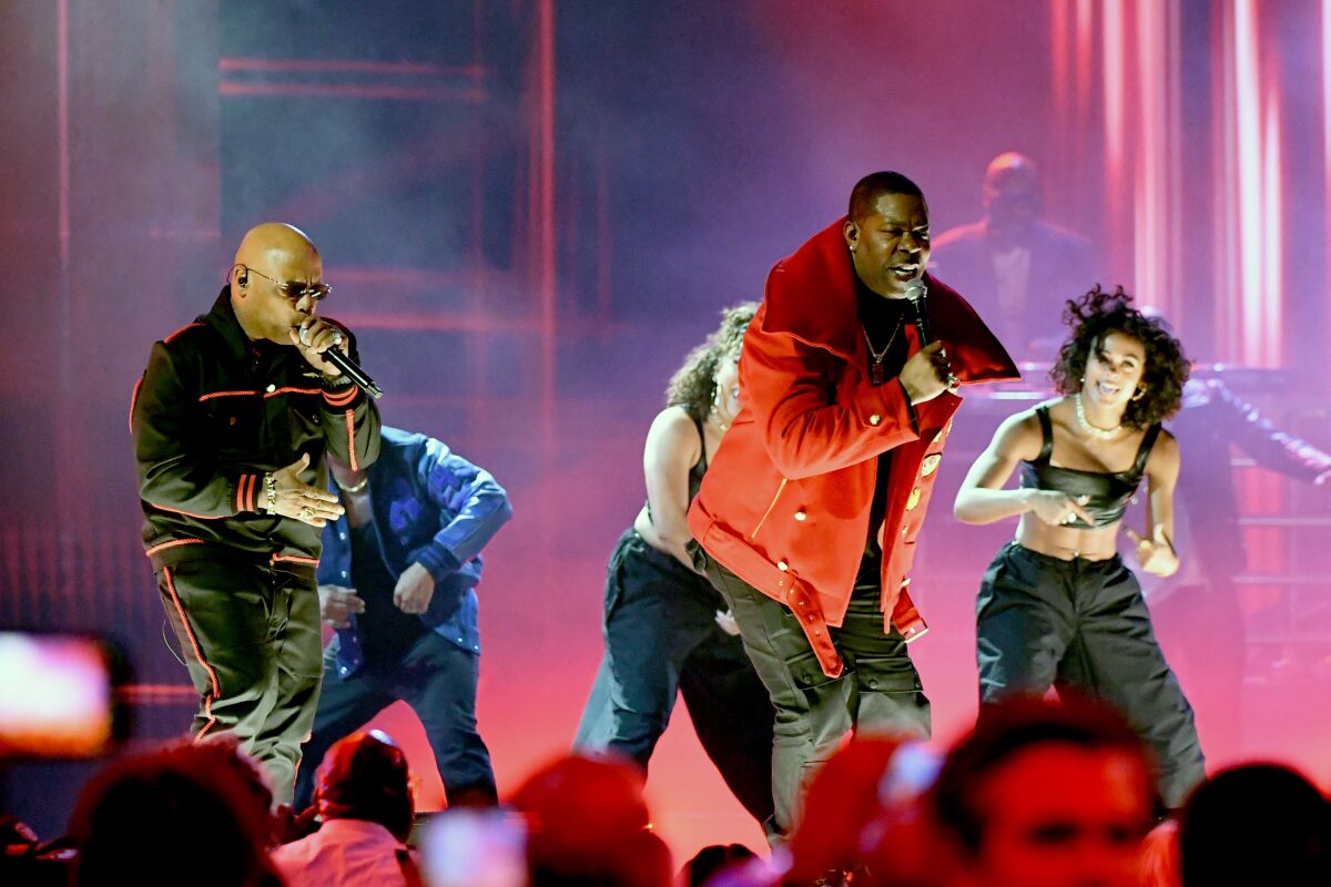 A rapper in a red jacket performs onstage