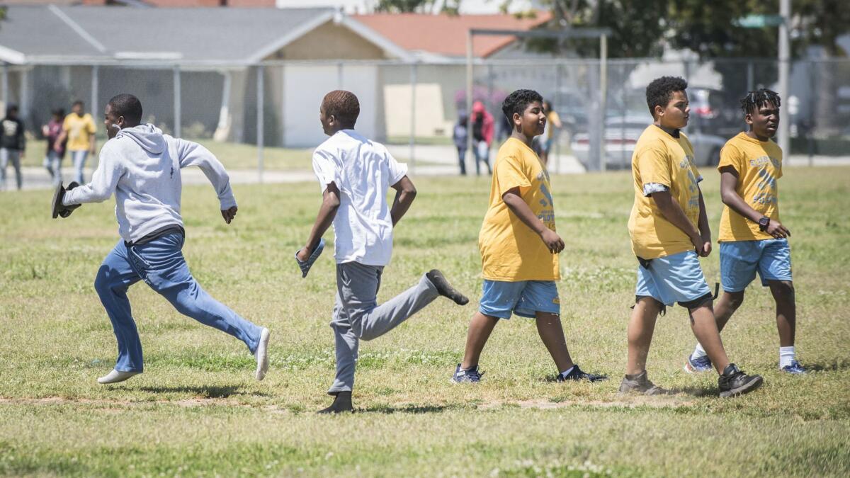 Different schools; different uniforms. Magnolia charter students, left, pass students from Curtiss Middle School, in yellow, during physical education. The playground is permanently split between the two schools.