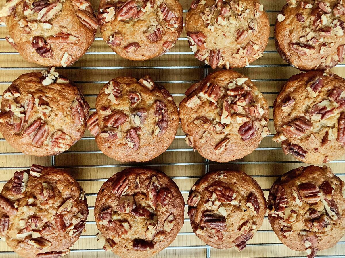 A dozen muffins with walnuts on top 