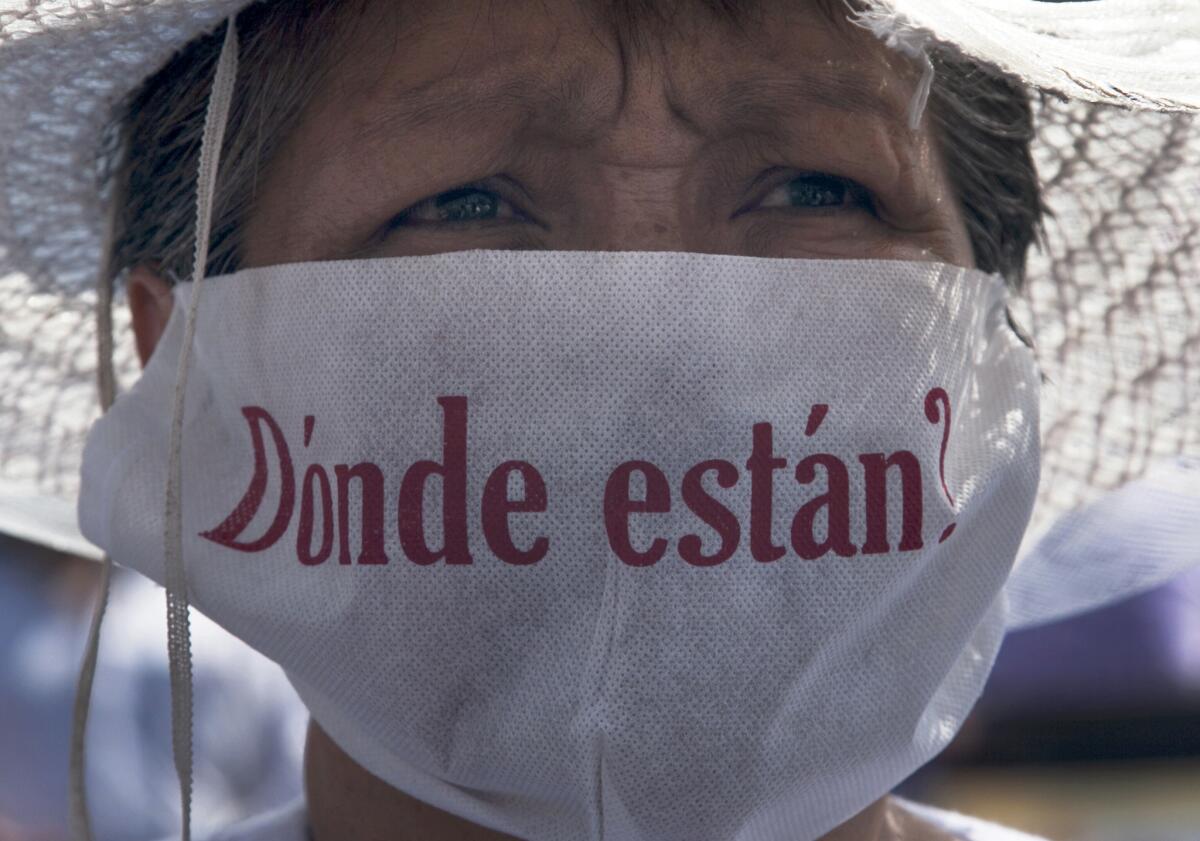 A mother with a face mask that reads in Spanish "Where are they?" marches along with hundreds of other mothers holding images of their missing relatives during Mother's Day on Sunday in Mexico City.