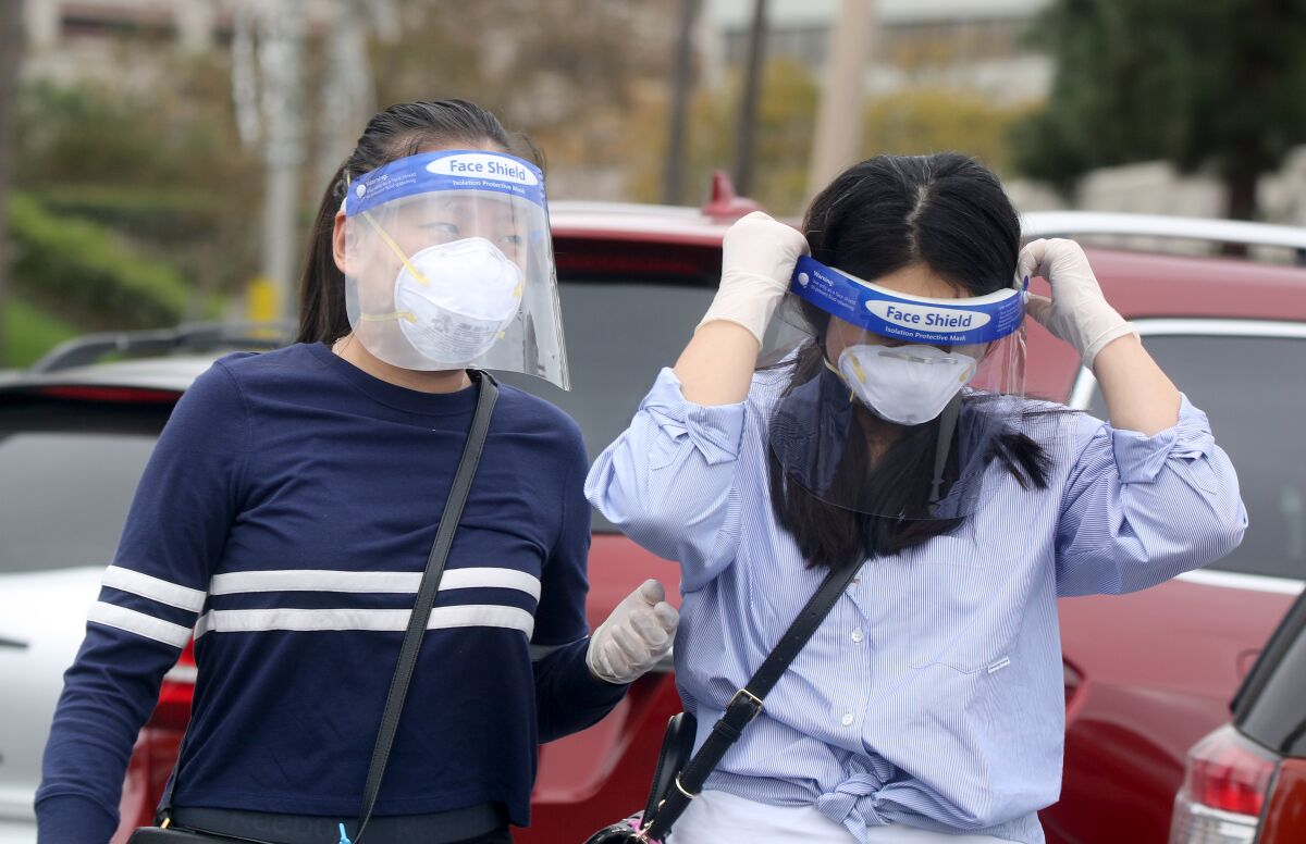 People wear masks and face shields while walking at Costa Mesa's South Coast Plaza on Friday. 