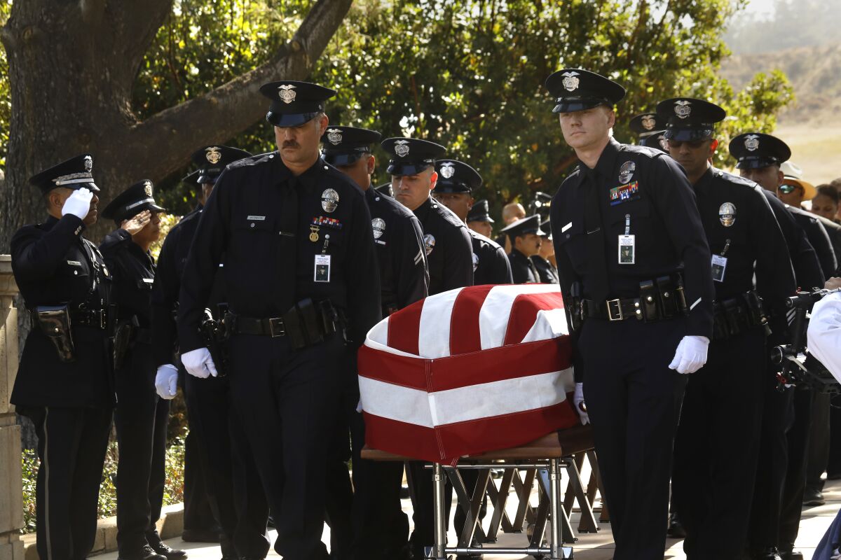  Uniformed officers carry a flag-draped casket 