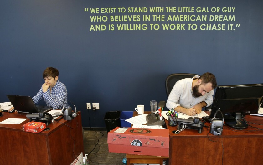 April Gracz, left, and Pano Giannakopoulos work near a wall displaying a Gravity Payments mission statement.