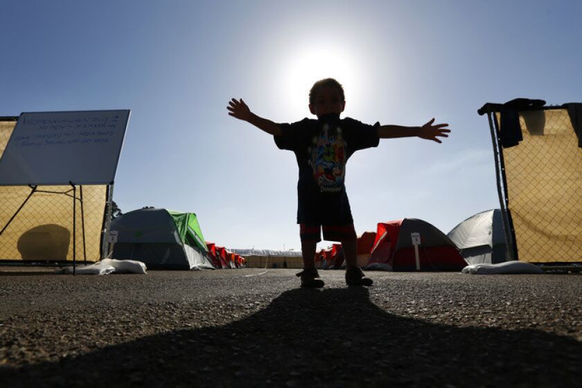 A child stands at the entrance to the women's section of the city-sanctioned homeless camp near Balboa Park Golf Course on Oct. 12 2017. Men are separated from women and children at the camp. (Photo by K.C. Alfred/The San Diego Union-Tribune)