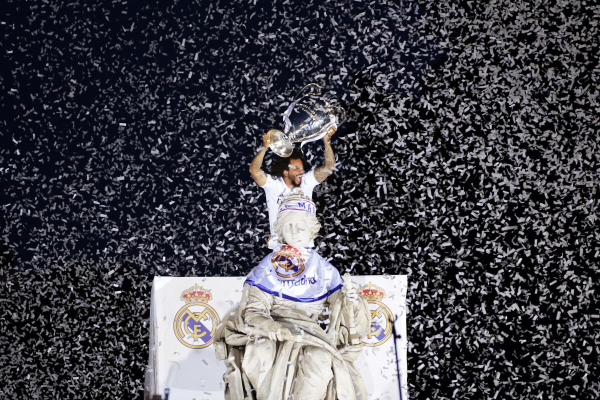 Real Madrid player Marcelo holds the trophy at the Cibeles square during a trophy parade in front of the City Hall in Madrid, Spain, Sunday, May 29, 2022. Real Madrid beat Liverpool 1-0 in the Champions League final in Paris. (AP Photo/Andrea Comas)