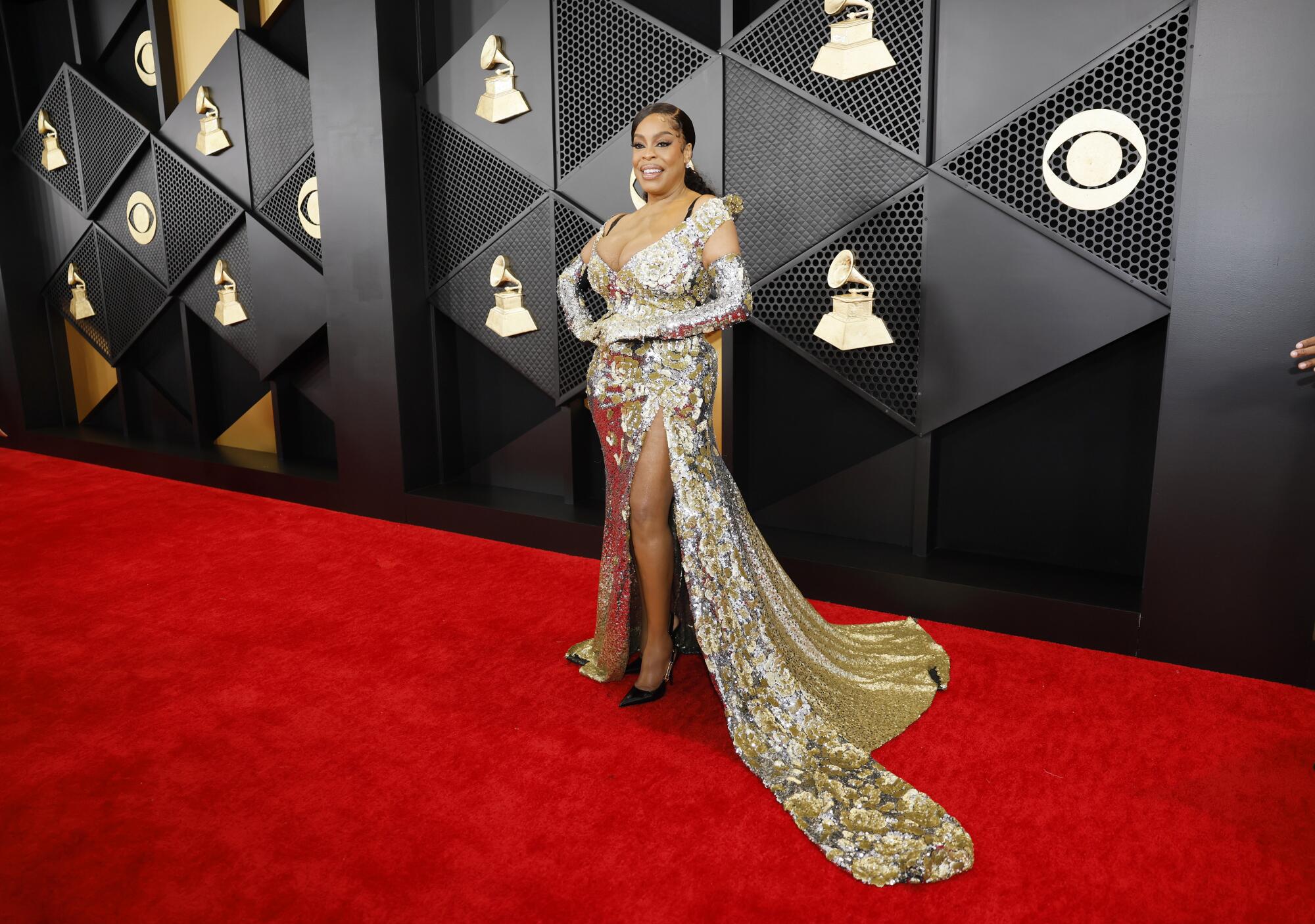 Niecy Nash wears a gold sequined gown with a long train 