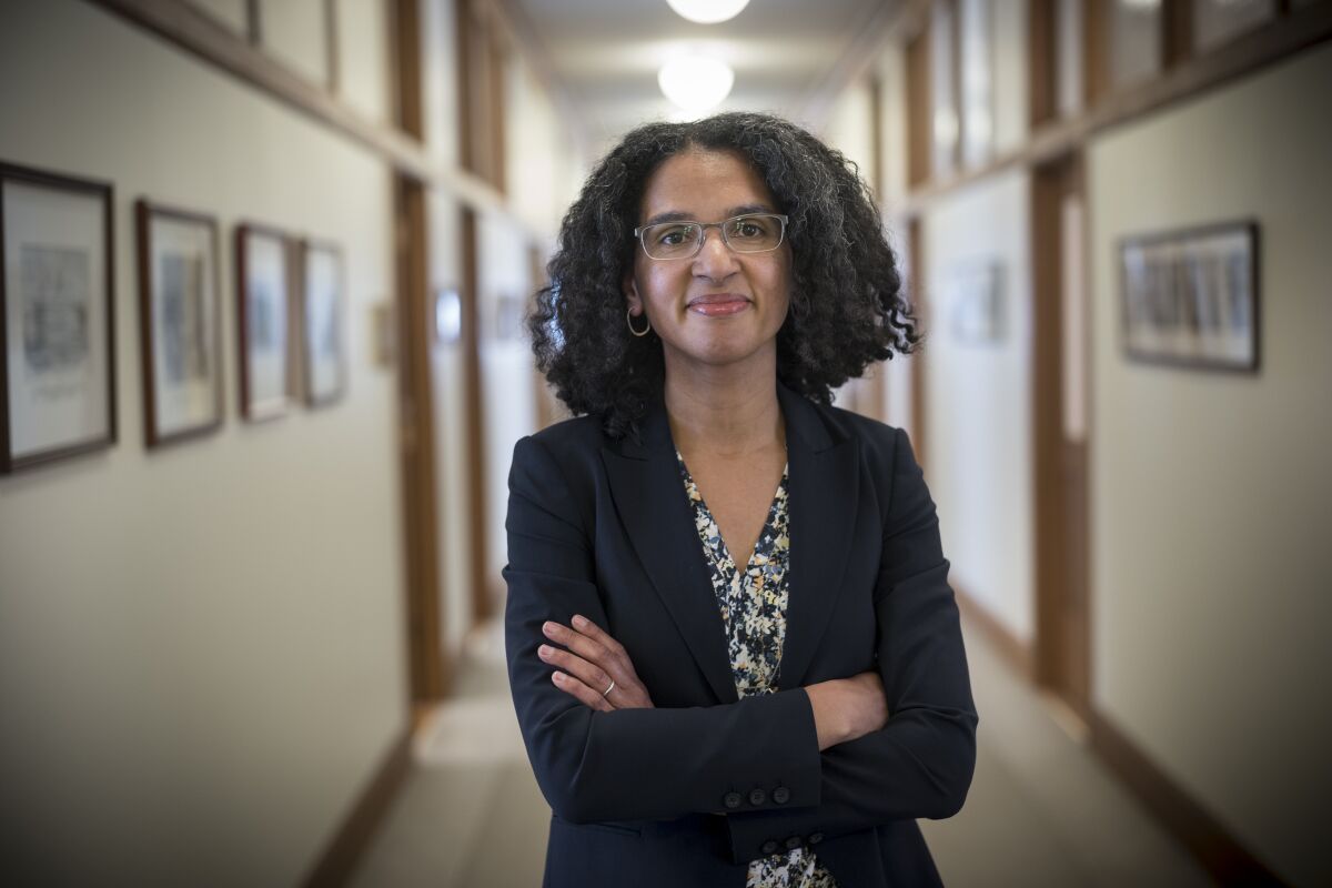 Justice Leondra Kruger stands, arms folded, in a hallway lined with photos