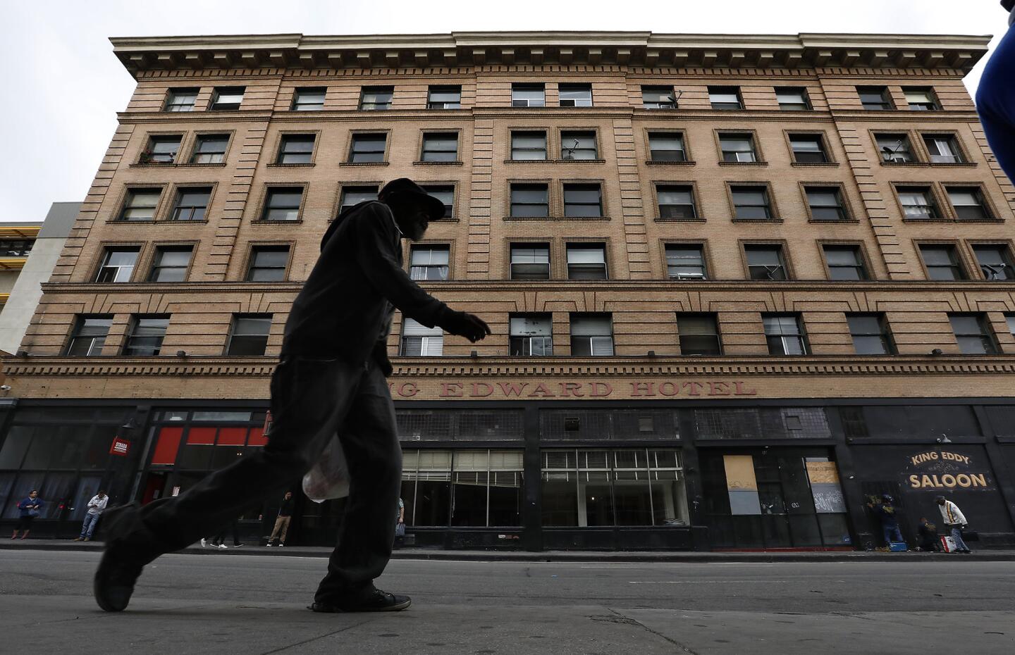 A pedestrian walks along 5th St. in downtown Los Angeles with the King Edward Hotel seen in the background. The Aids Healthcare Foundation has purchased the 106 year old hotel and plans to lease its 150 rooms to homeless people.