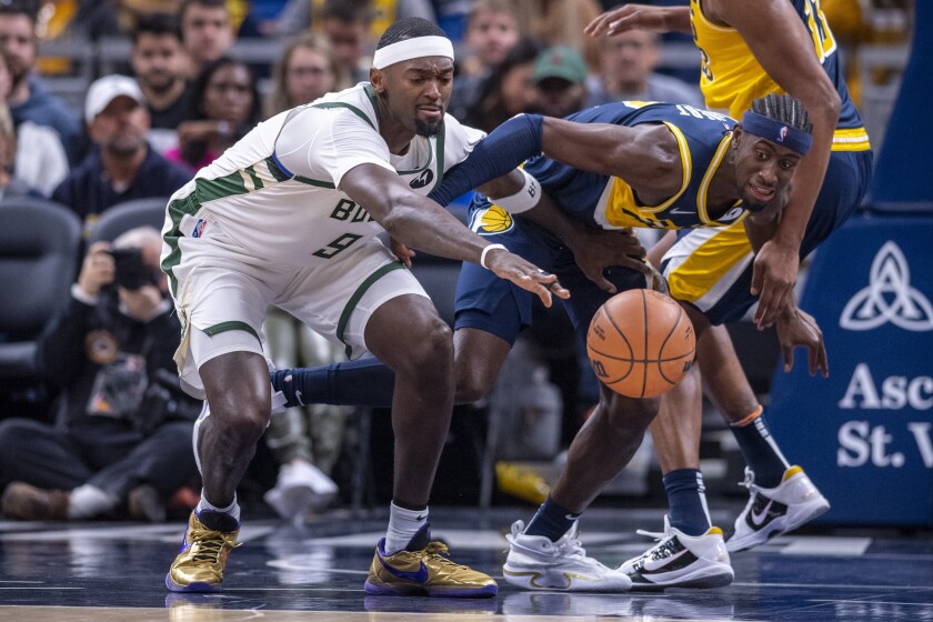 Milwaukee Bucks center Bobby Portis (9) and Indiana Pacers guard Caris LeVert (22) battle for the ball during the first half of an NBA basketball game in Indianapolis, Sunday, Nov. 28, 2021. (AP Photo/Doug McSchooler)