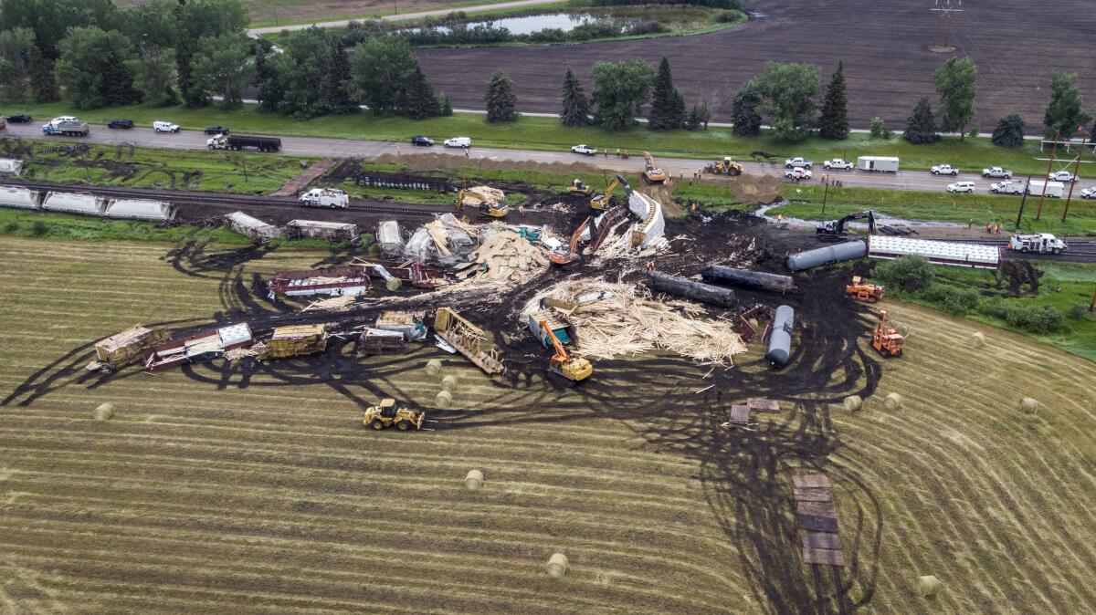 Crews work to clean up a spill after the derailment of a 20-car train carrying "tar sand'' and lumber near Blackfalds, Alberta, Canada, Saturday, July 3, 2021. (Jeff McIntosh/The Canadian Press via AP)