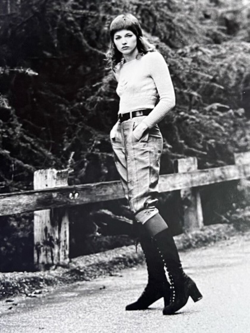 foto em preto e branco de mulher com botas pretas altas, jeans e camiseta do lado de fora 