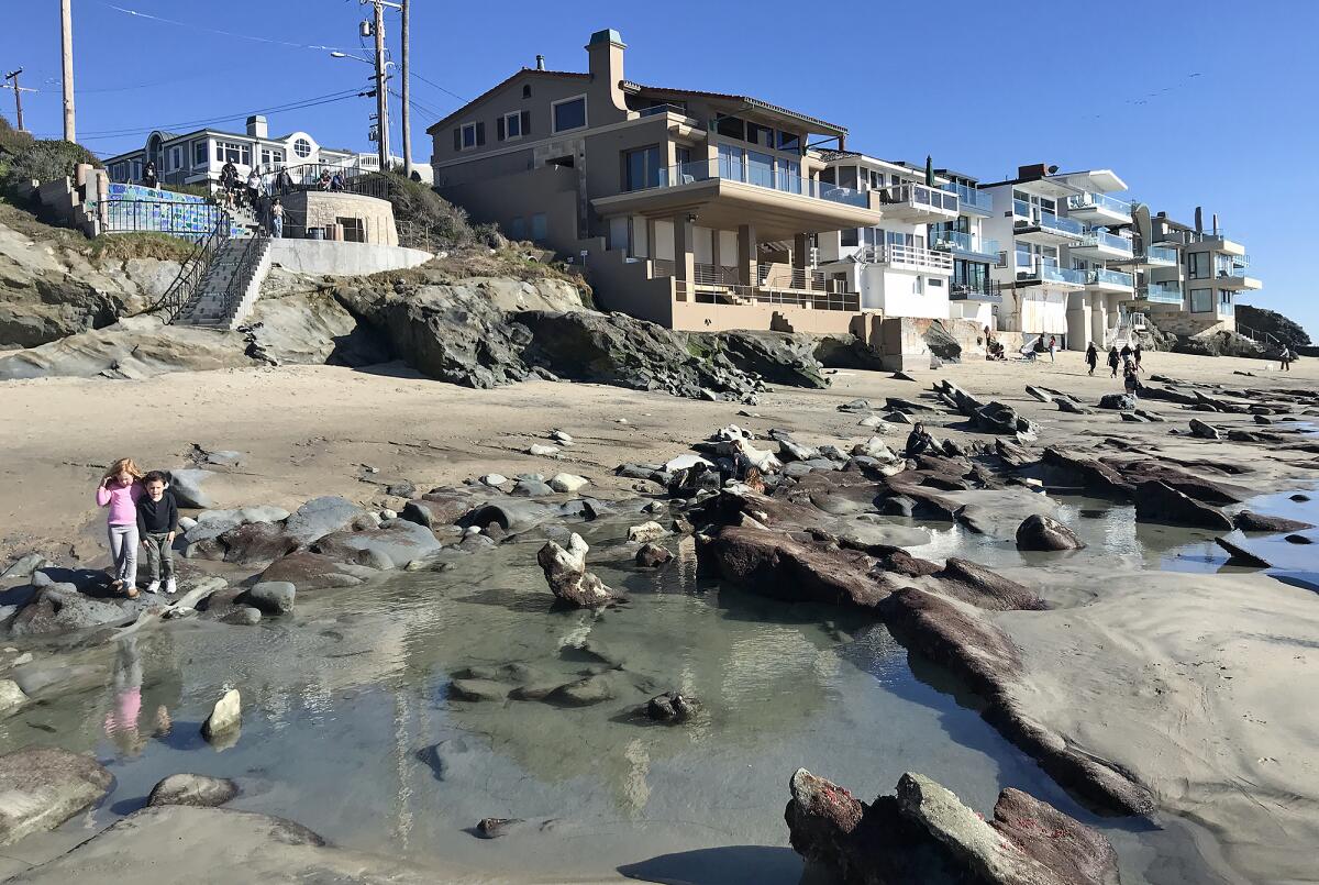 Puddles of left behind sea water reflect homes on the beach front.