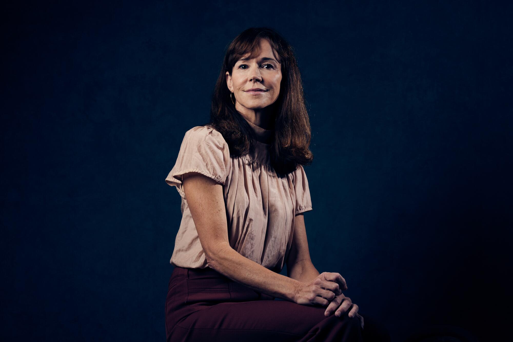 A woman sits and smiles.