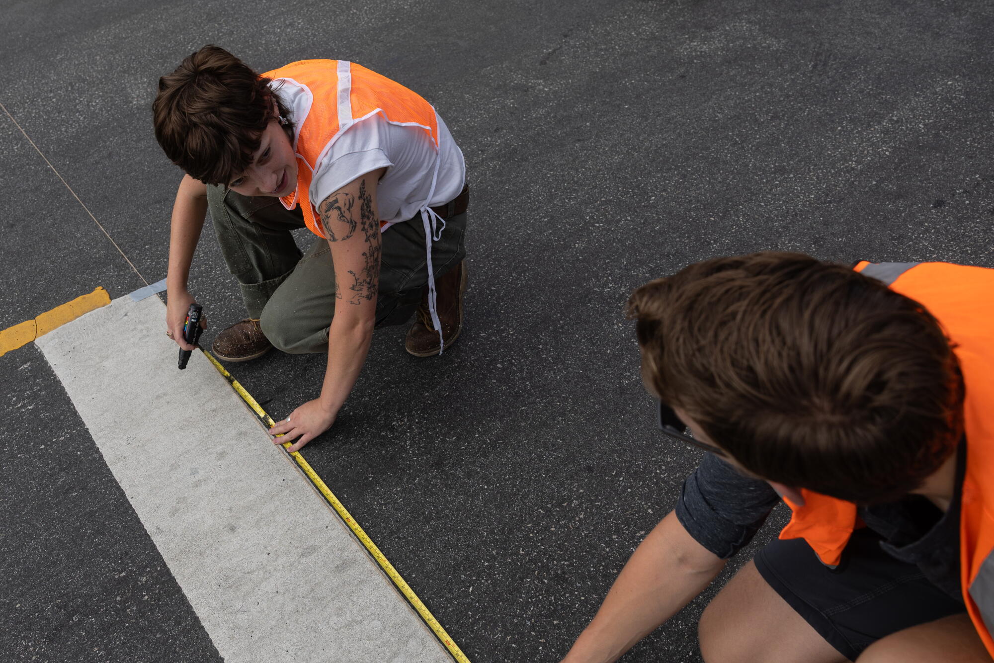Venus, a volunteer, measures the spacing betwixt the lines of a crosswalk.