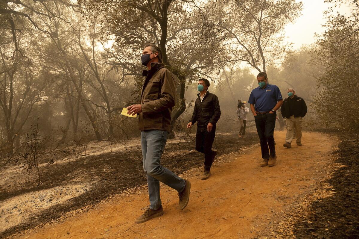 Gov. Gavin Newsom takes notes as he tours the North Complex fire zone.