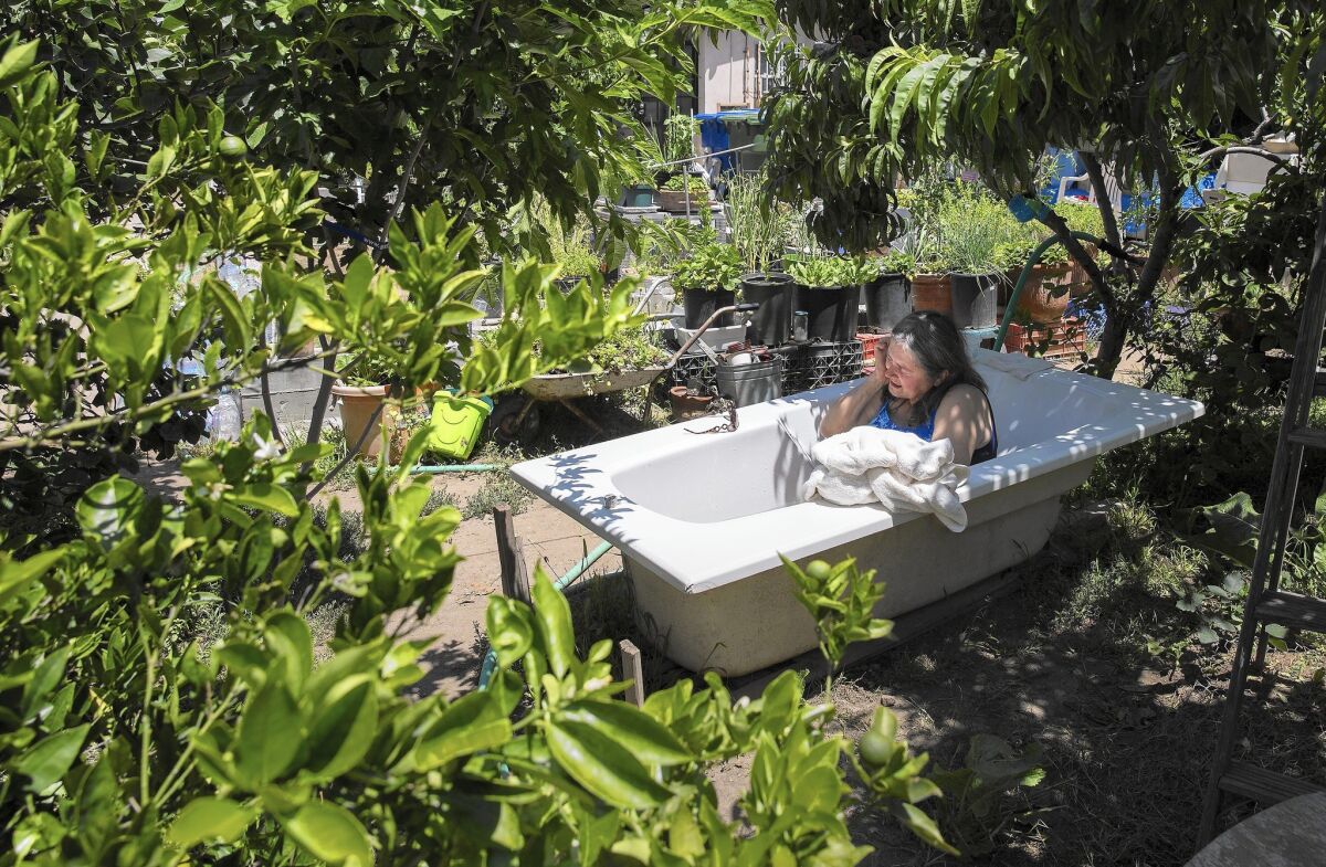 Agneta Dobos, 67, bathes in an outdoor tub on her property in Tujunga. (Brian van der Brug / Los Angeles Times)