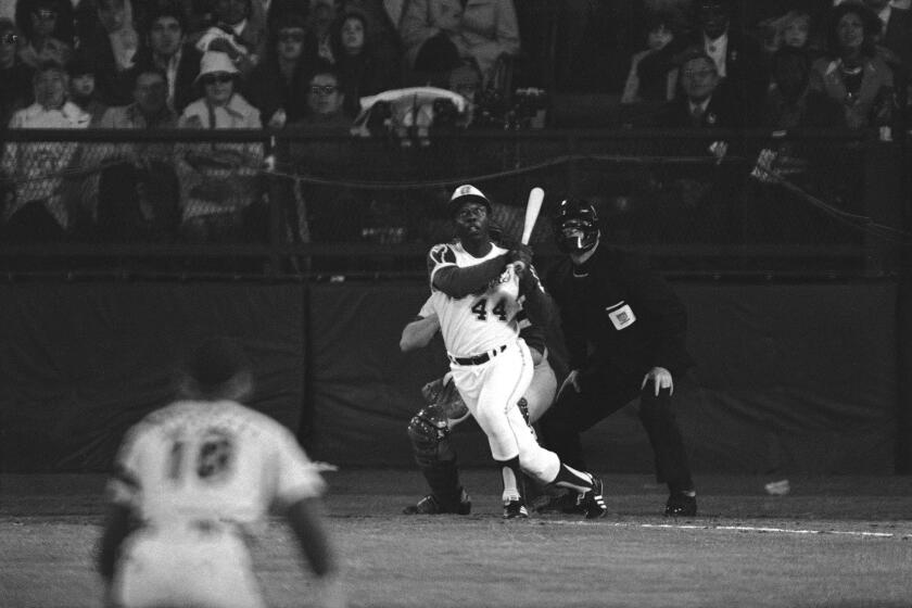 FILE - Atlanta Braves' Hank Aaron eyes the flight of the ball after hitting his 715th career homer in a game against the Los Angeles Dodgers in Atlanta, Ga., Monday night, April 8, 1974. Aaron broke Babe Ruth's record of 714 career home runs. Dodgers southpaw pitcher Al Downing, catcher Joe Ferguson and umpire David Davidson look on. Just in time for the 50-year anniversary of Hank Aaron's record 715th home run, Charlie Russo is making available video he shot of the homer. (AP Photo/Harry Harris, File)