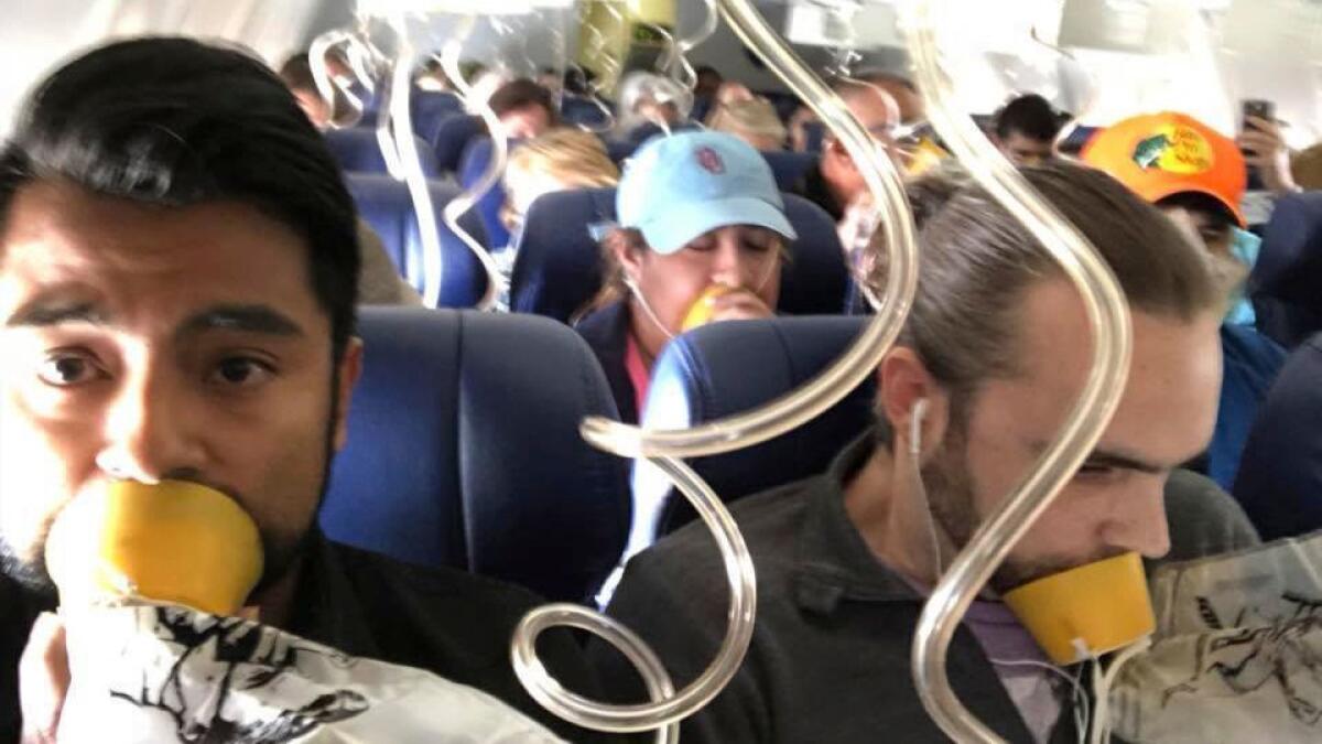 Marty Martinez, left, and other passengers breathe through oxygen masks after a jet engine blew out on their Southwest Airlines jet on Tuesday.