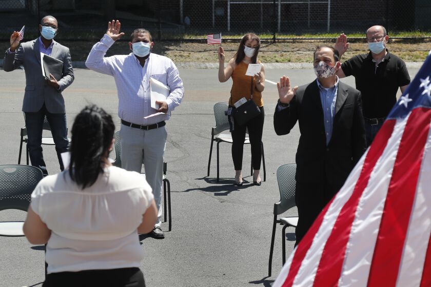 Varias personas prestan juramento para convertirse en ciudadanos estadounidenses afuera del edificio del Servicio de Ciudadanía e Inmigración el jueves 4 de junio de 2020, en Lawrence, Massachusetts. (AP Foto/Elise Amendola)
