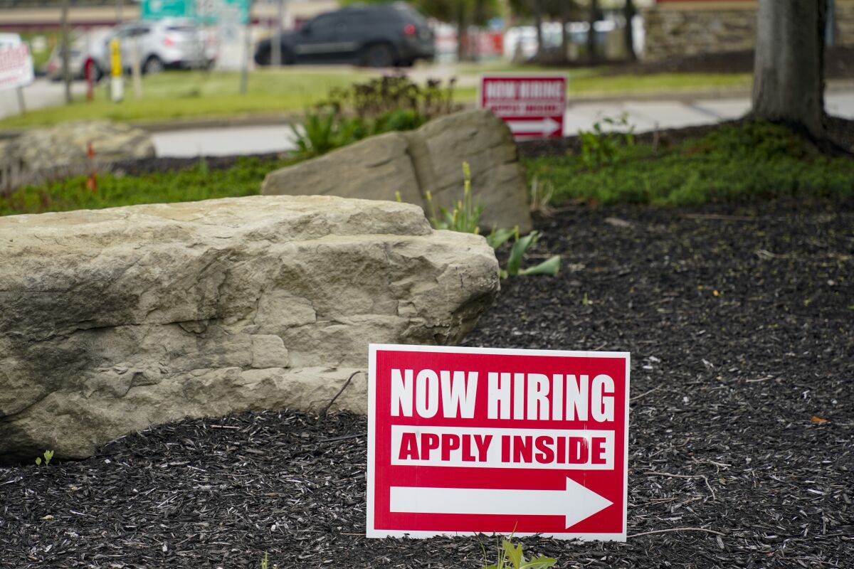 A sign with an arrow says, "Now hiring: Apply inside."
