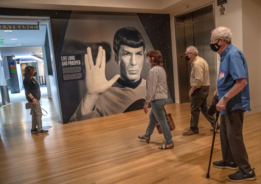 People walk through a gallery with a big poster of Spock giving the Vulcan salute.