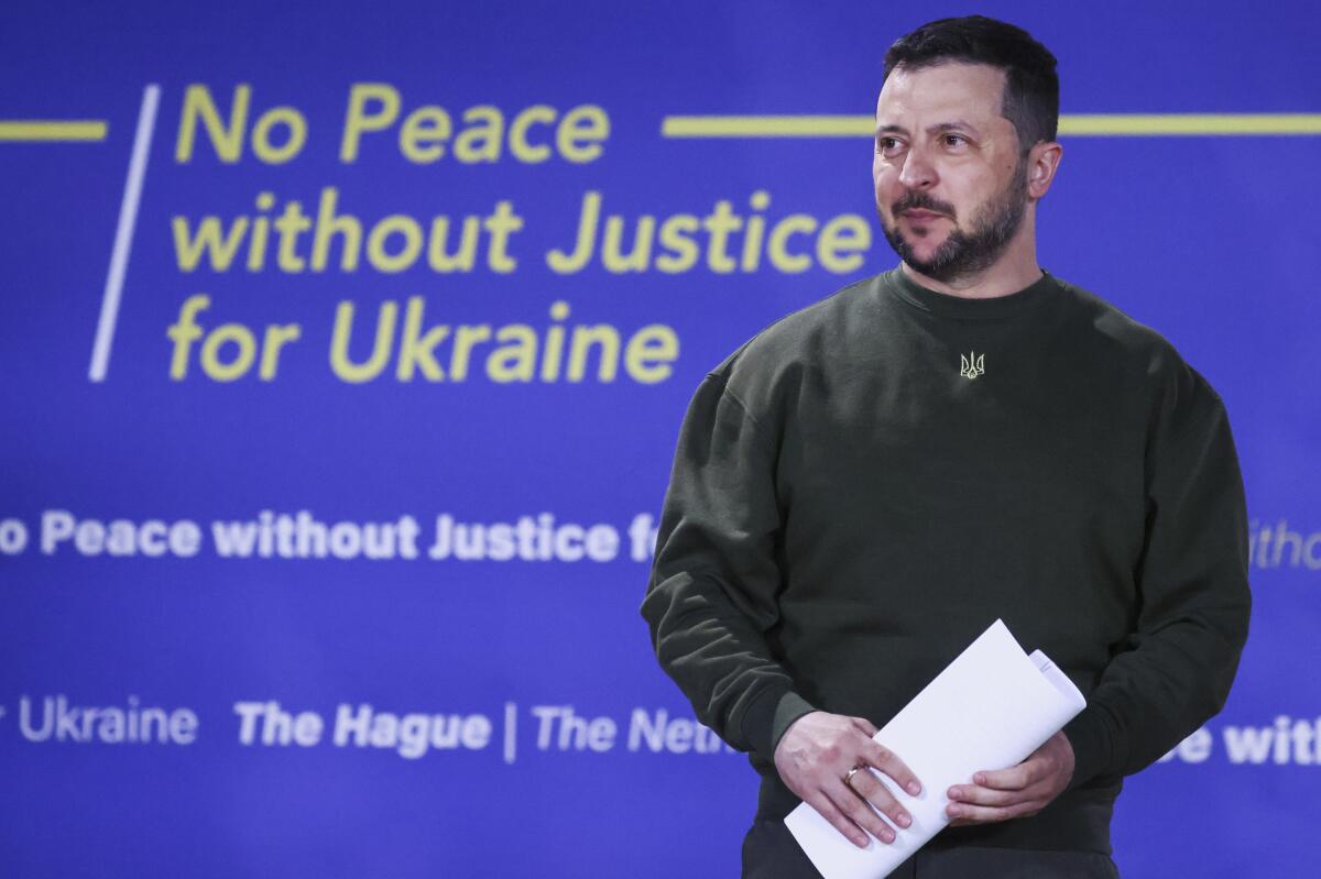 Ukrainian President Volodymyr Zelensky in front of a blue background with the words No Peace without Justice for Ukraine
