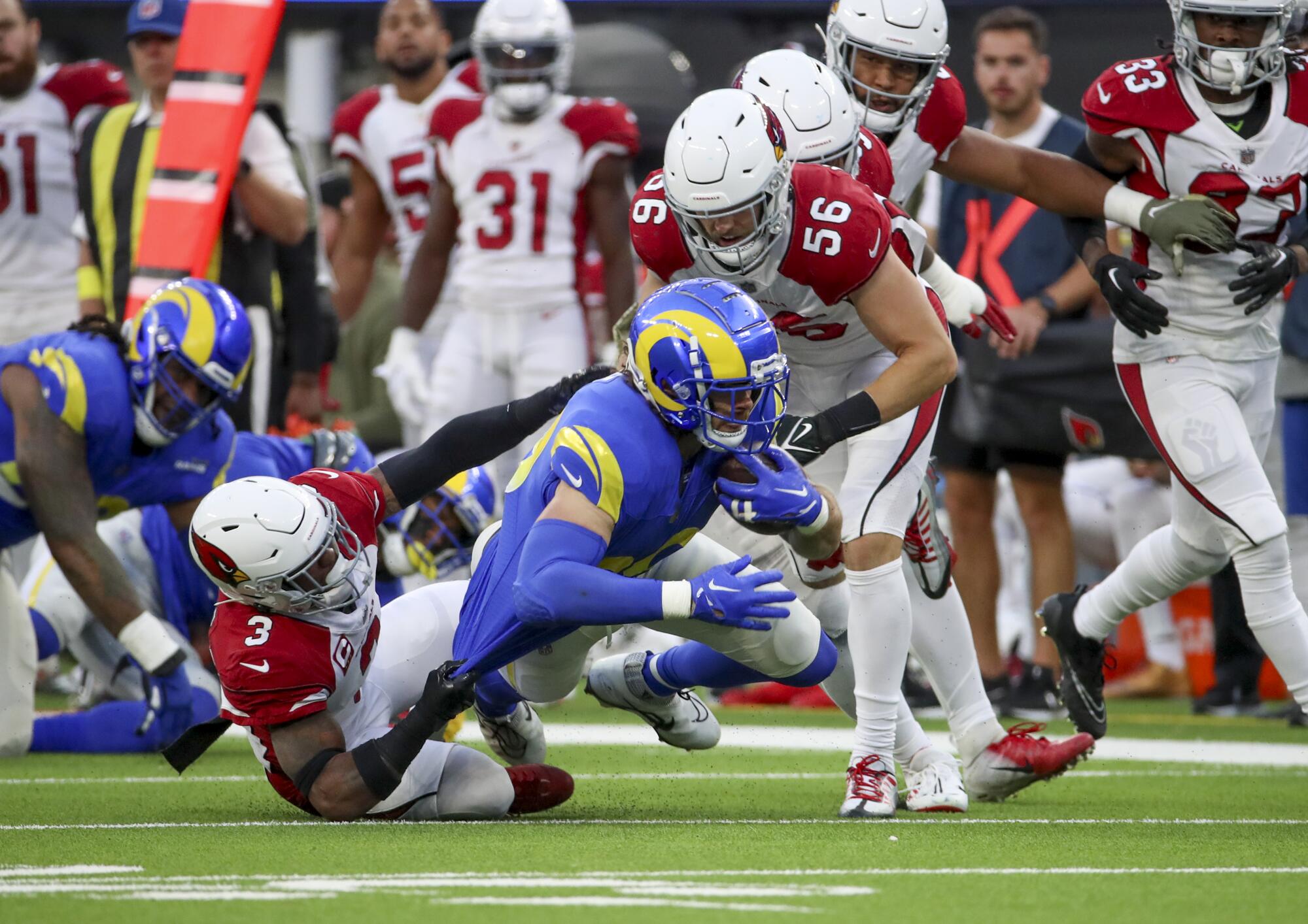 Cardinals safety Budda Baker, left, and linebacker Ben Niemann tackle Rams tight end Tyler Higbee.