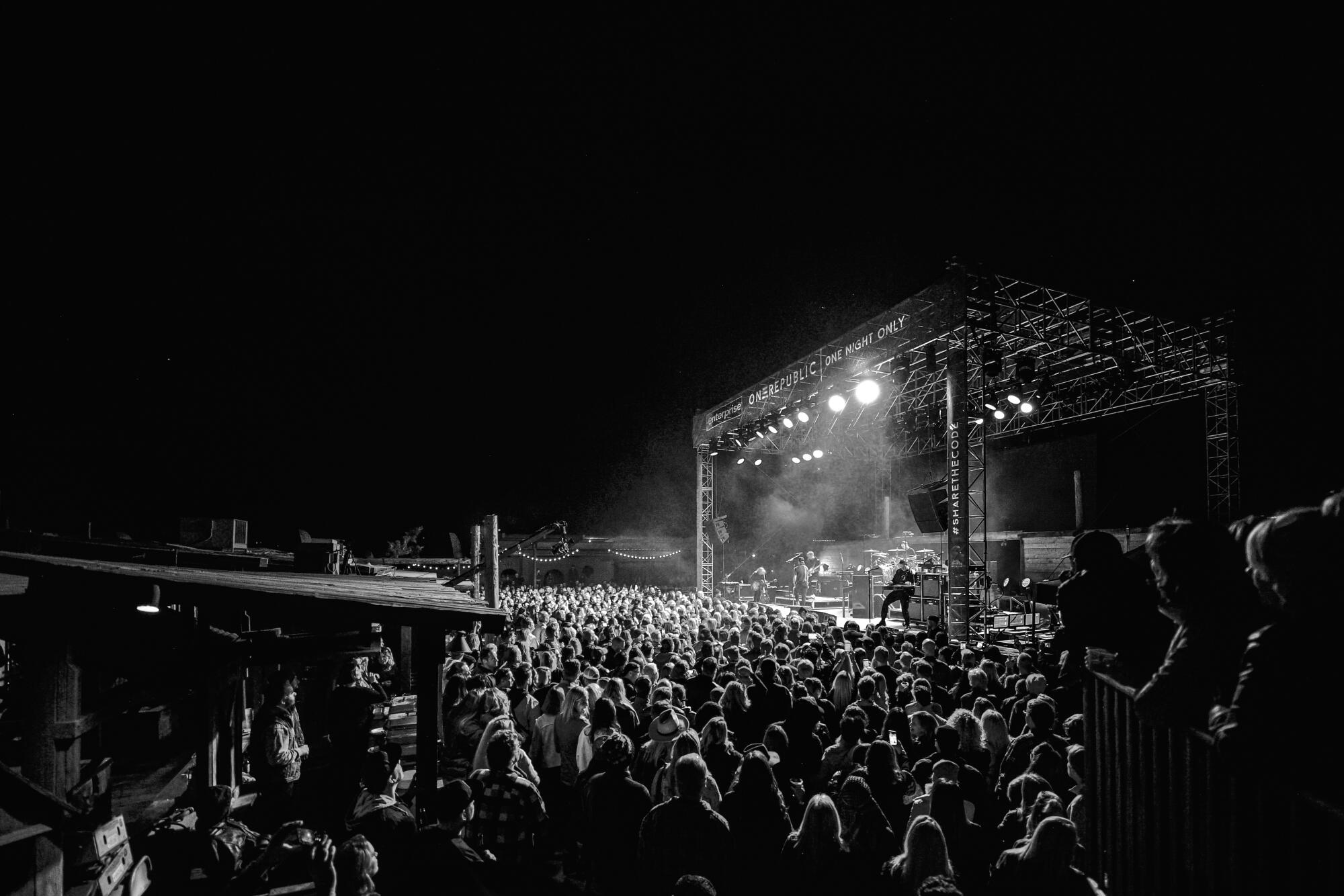 A crowd of people watch a band perform on an outdoor stage