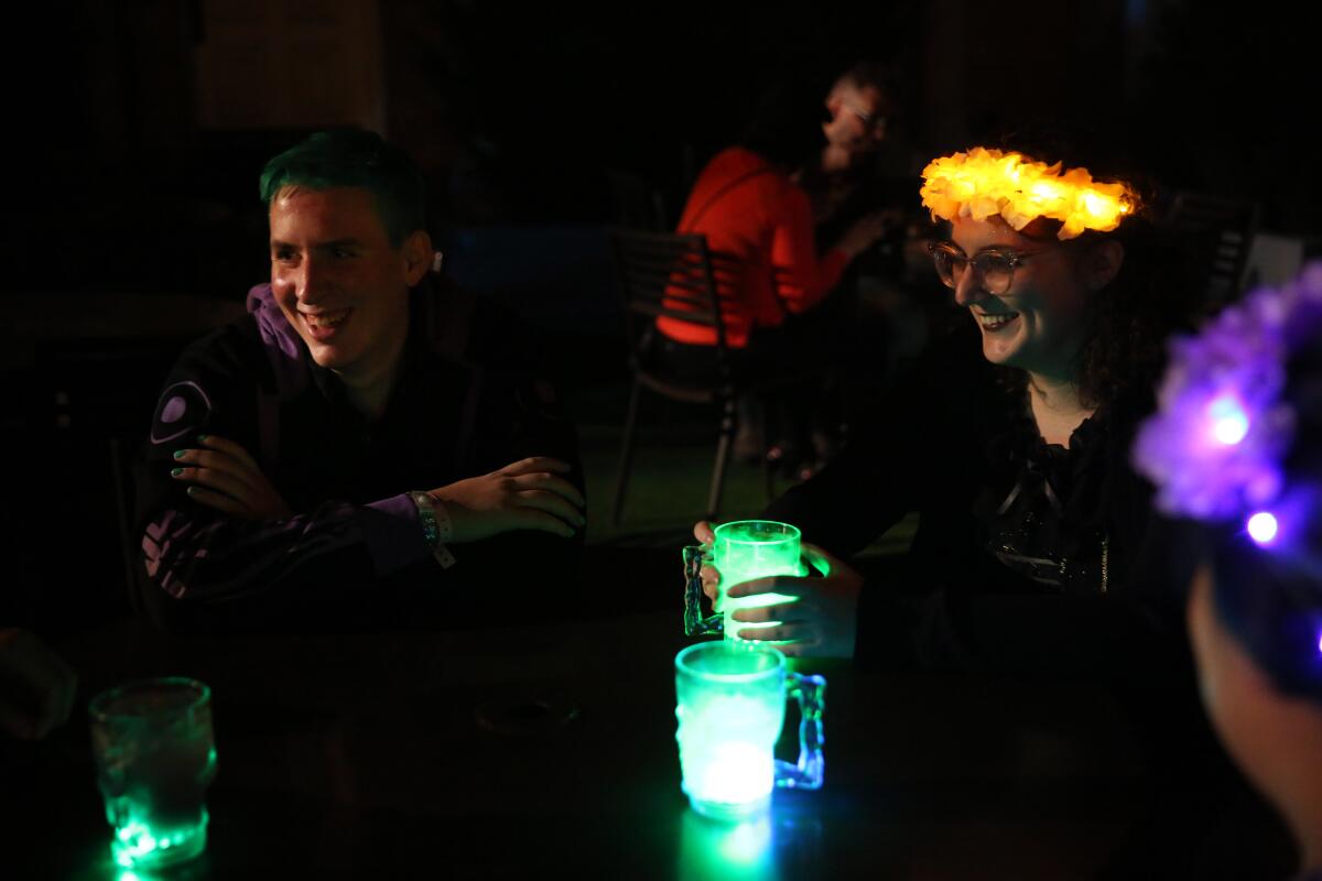 Sam Saks-Fithian, left, Sli Murray and Ivy Lim sip on Halloween Horror Nights cocktails at Universal Studios Hollywood. The theme park is serving foods inspired by '80s pop culture and are visually interesting with hopes of people posting them to social media.