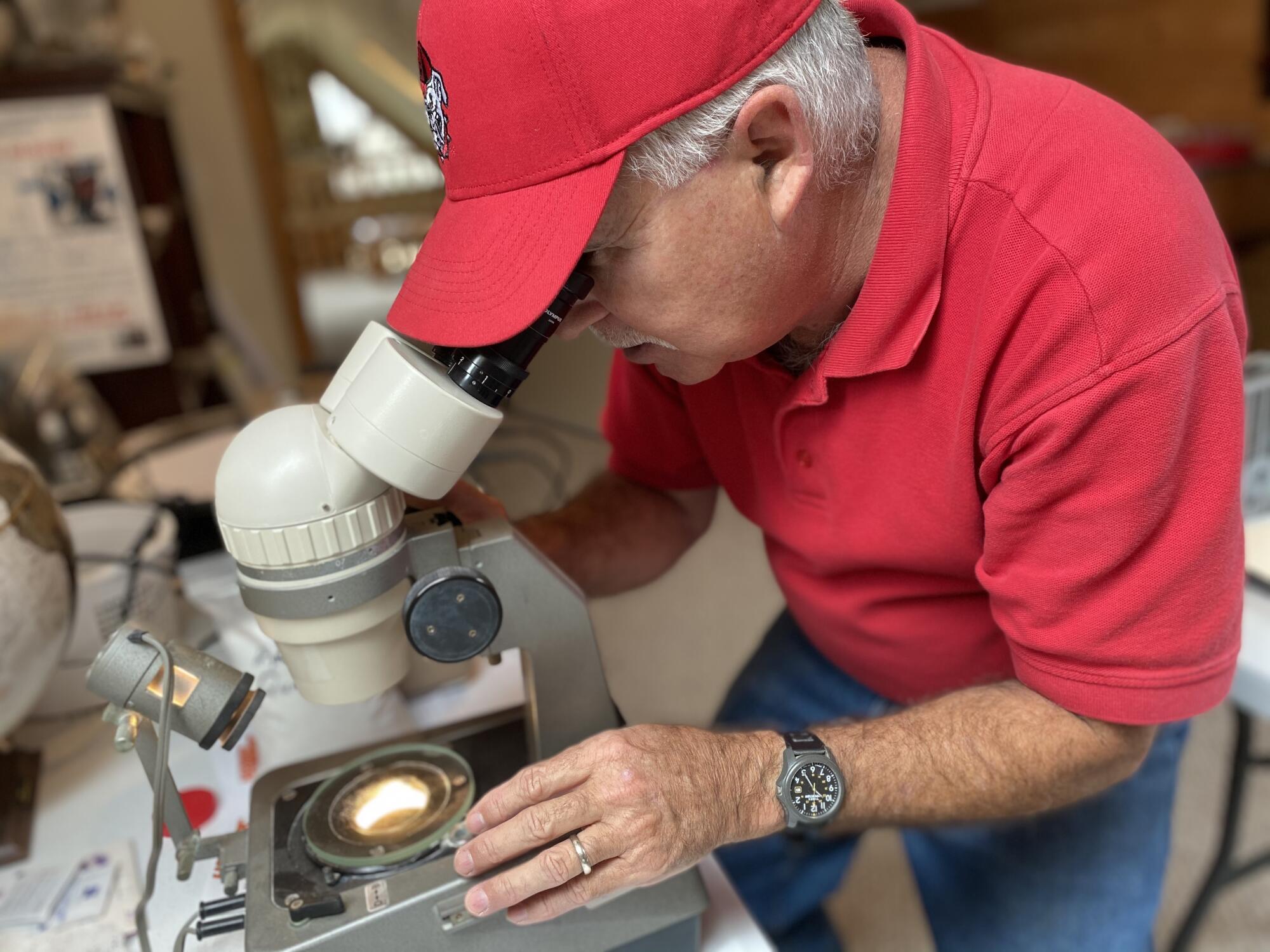 Alex Glover, retired head geologist, looks at grains of high-purity quartz sand under a microscope.