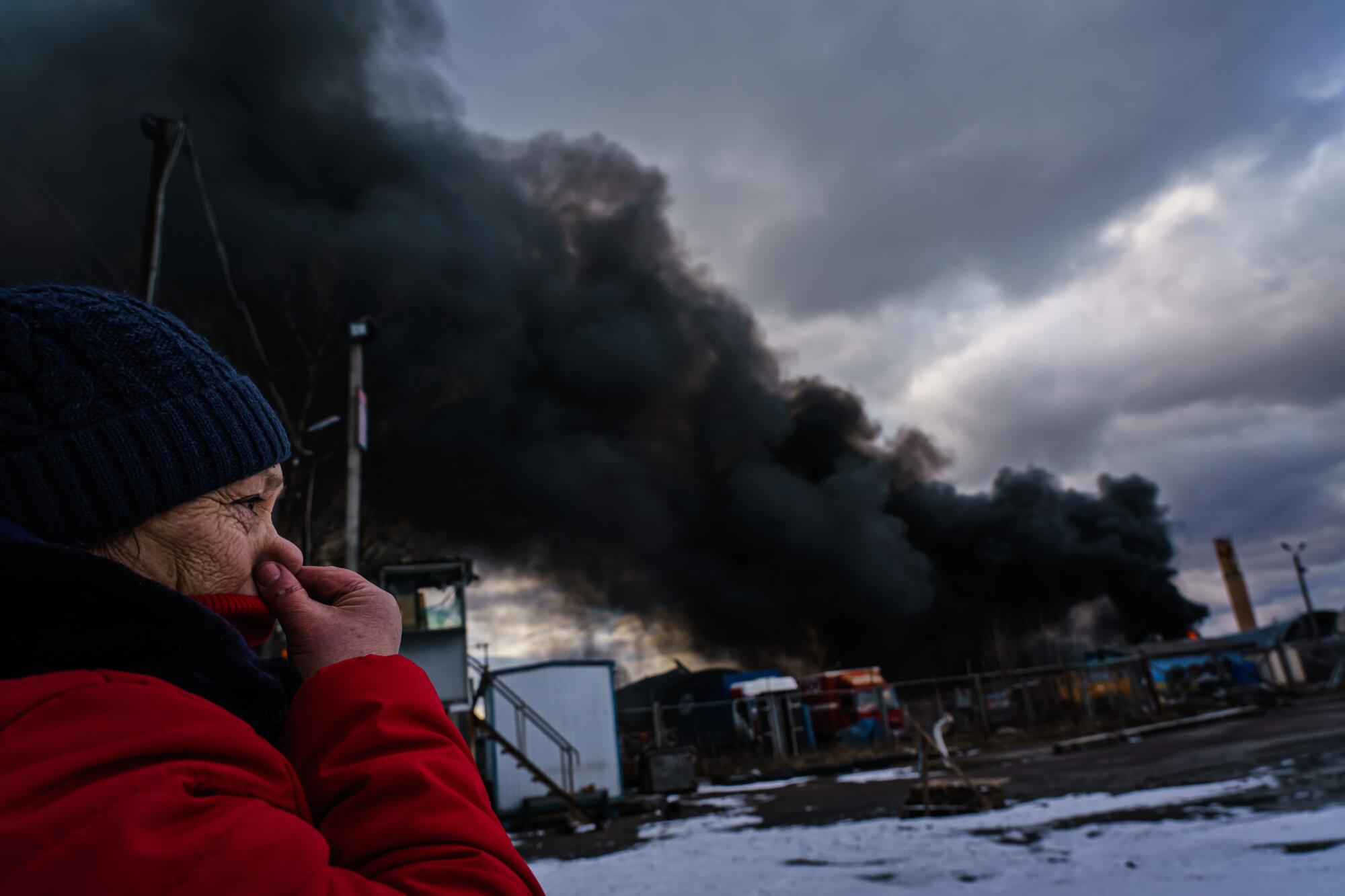 A woman closes her nose to prevent inhaling the smell of chemicals caused by a plume of smoke