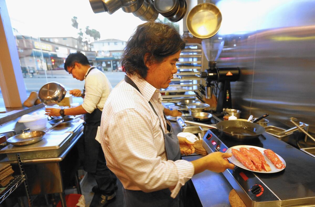 Chef Gary Menes, right, prepares Wagyu beef as part of his six-course tasting menu at Le Comptoir in the Hotel Normandie.