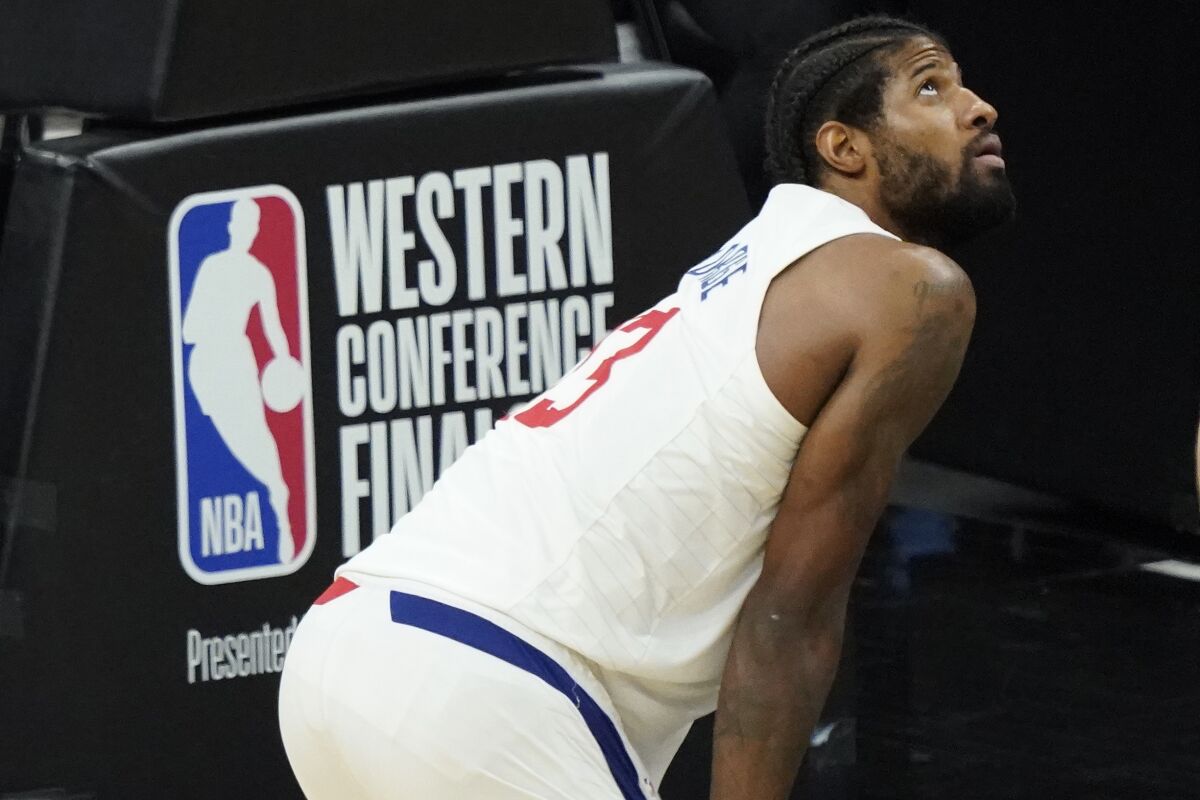 Clippers guard Paul George bends in front of a Western Conference Finals sign