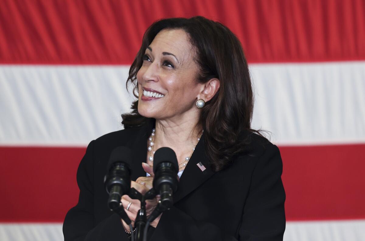 Kamala Harris speaks into a microphone with the U.S. flag in the background