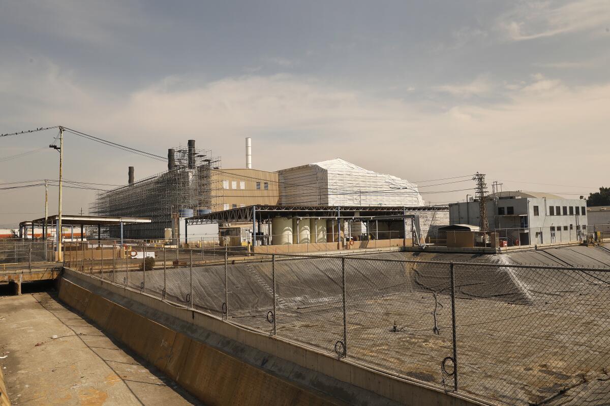 An industrial facility behind a chain link fence. 