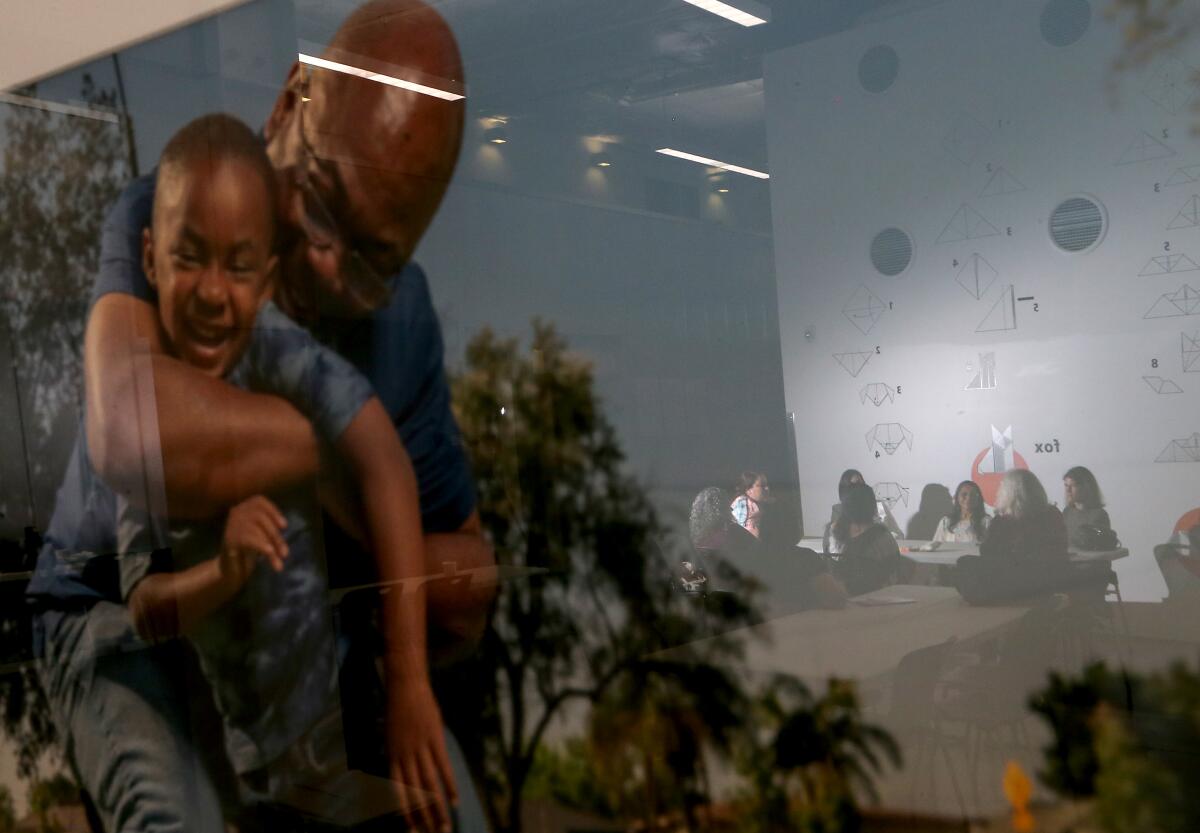 Staff members at Children's Institute in Los Angeles are reflected in a picture frame as they meet.