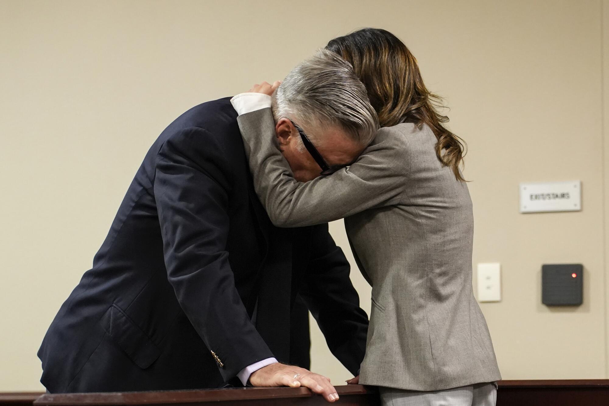 Hilaria Baldwin speaks to husband, Alec Baldwin, and wraps her arms around his neck while he looks down.